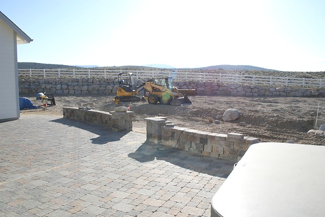 Paver patio with seating walls and boulder retaining walls in background